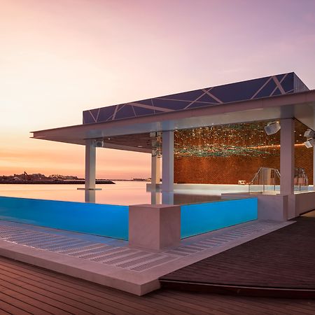Five Palm Jumeirah Dubai Esterno foto The image shows a modern architectural structure featuring an outdoor swimming pool. The building has a sleek design with large glass walls and a roof that appears to be made of transparent material. The front side has an infinity pool that blends wi