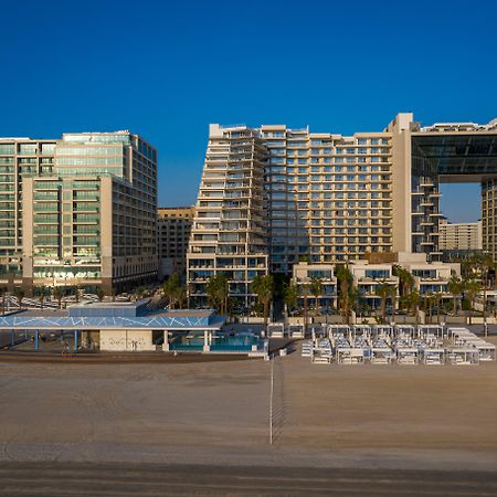 Five Palm Jumeirah Dubai Esterno foto The photo shows a modern beachside hotel complex. It features several large buildings with sleek, contemporary architecture. The structures include glass facades and distinctive shapes, contributing to a luxurious appearance. In the foreground, there