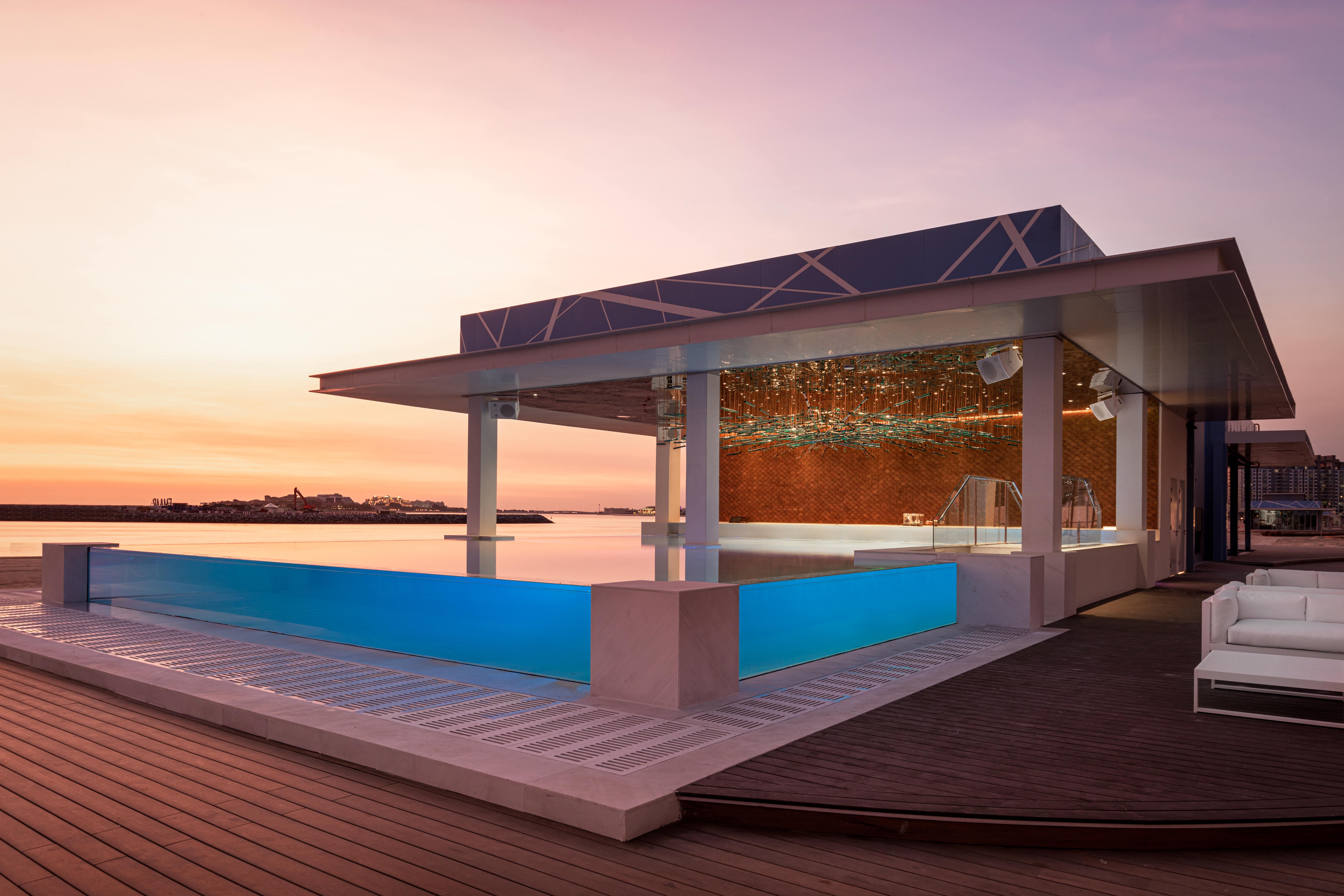 Five Palm Jumeirah Dubai Esterno foto The image shows a modern architectural structure featuring an outdoor swimming pool. The building has a sleek design with large glass walls and a roof that appears to be made of transparent material. The front side has an infinity pool that blends wi