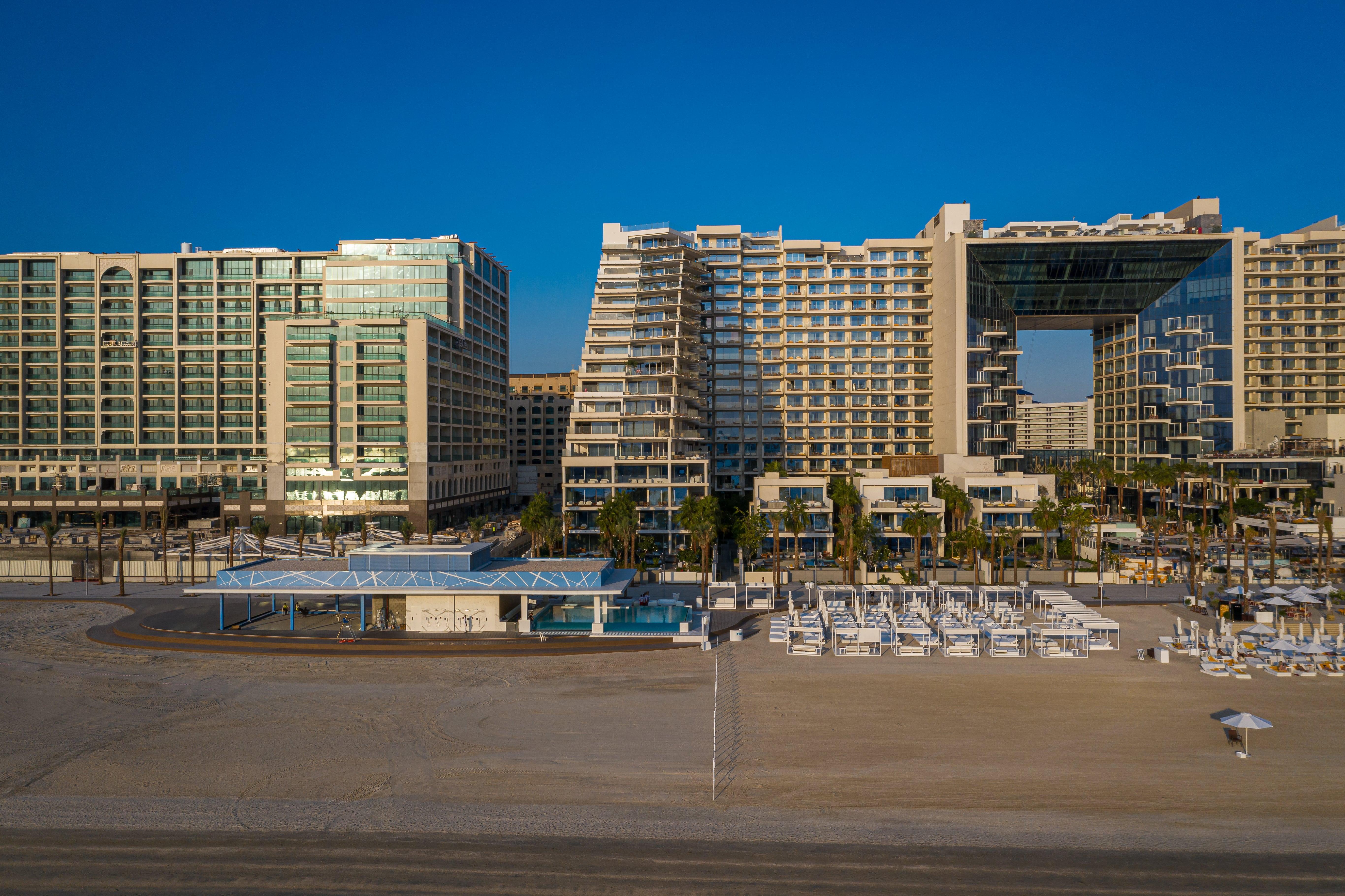 Five Palm Jumeirah Dubai Esterno foto The photo shows a modern beachside hotel complex. It features several large buildings with sleek, contemporary architecture. The structures include glass facades and distinctive shapes, contributing to a luxurious appearance. In the foreground, there